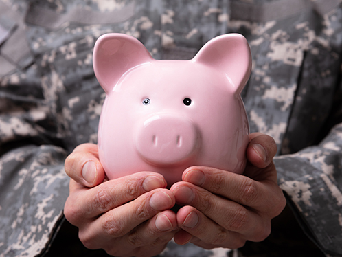 an army officer in uniform, holding a pink ceramic piggy bank cradled in hands.