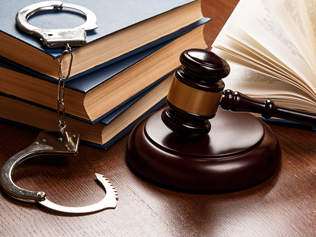 Gavel, books and handcuffs on wood table