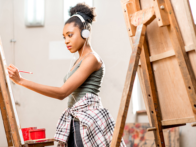  closeup of young African American female Student painting in art studio