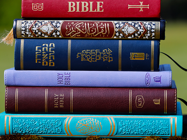 A collection of books, predominantly bibles and religious texts, stacked in an orderly manner