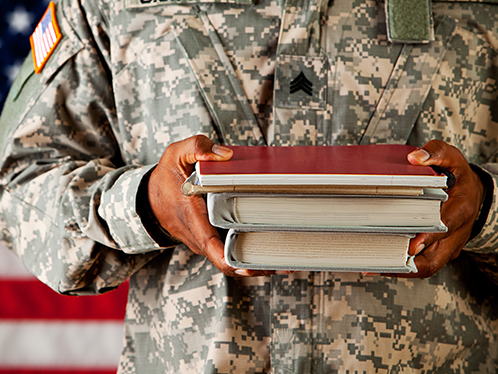 A close-up image of a black army officer student's hands holding a small stack of books.