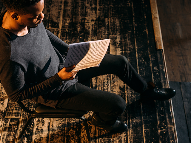 african american male actor student holding script on stage during rehearse or audition