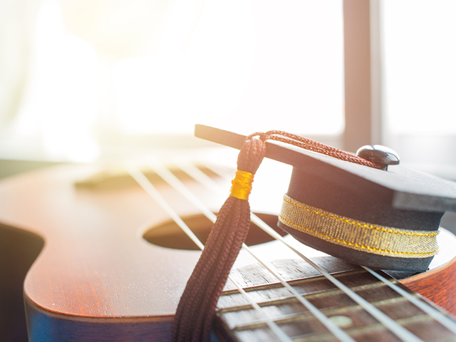 mini graduation cap sitting on top of a guitar