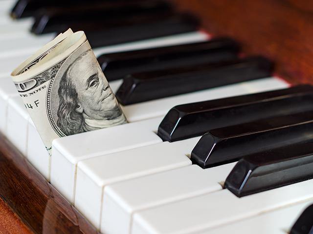Dollar bill sticking out of piano keys