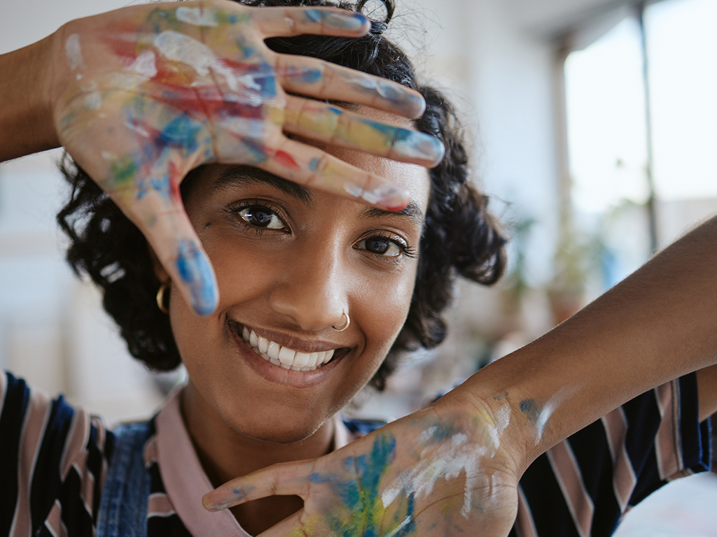 closeup of young African-American artist hands painting picture in workshop