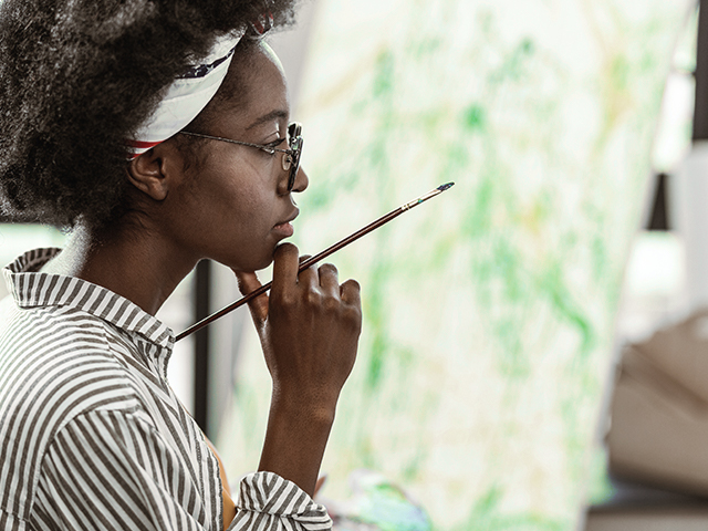 African-American art student feeling thoughtful working on new painting